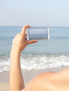 Kumsalda akıllı telefon kullanan bir kadın.