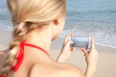 Kumsalda akıllı telefon kullanan bir kadın.