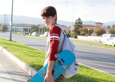 boy carrying his skateboard while walking