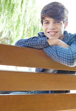 boy sitting and relaxing on a park wooden bench