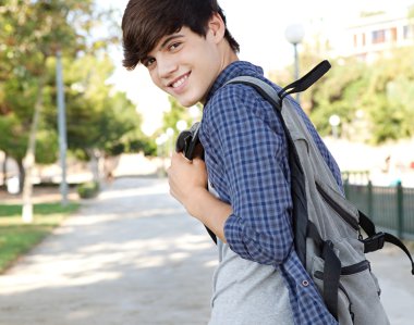 student boy walking on a path at a college campus