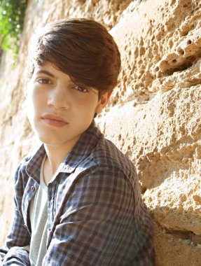 student boy leaning on an old and aged stone wall
