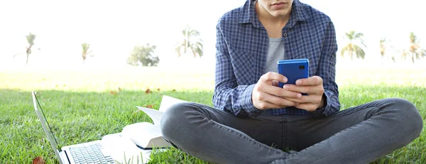 Boy in a park using his smartphone — Stok fotoğraf