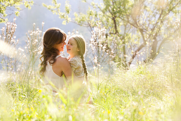 Мать и дочь обнимаются на весеннем поле
