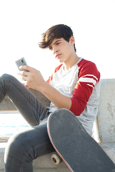 Menino usando um smartphone com um skate — Fotografia de Stock