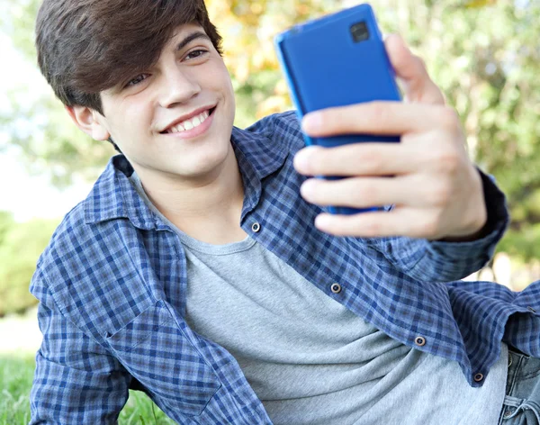 Menino usando um smartphone para tirar uma foto selfy — Fotografia de Stock