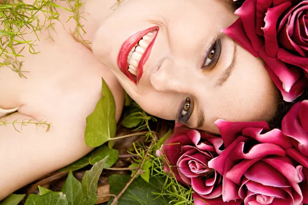 Mujer acostada en un bosque con un vestido de cabeza de rosas rojas — Foto de Stock