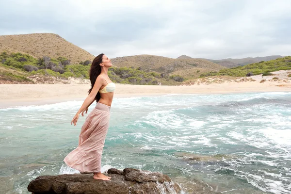 Mulher de pé sobre uma rocha junto ao mar — Fotografia de Stock