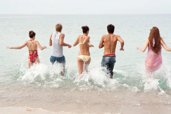 Friends running together into the sea — 图库照片