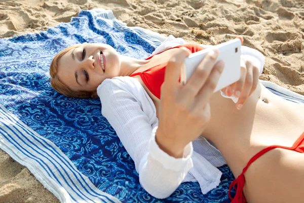 Kobieta za pomocą smartfona na plaży — Zdjęcie stockowe