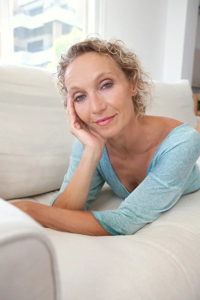 Femme sur un canapé blanc à la maison — Photo