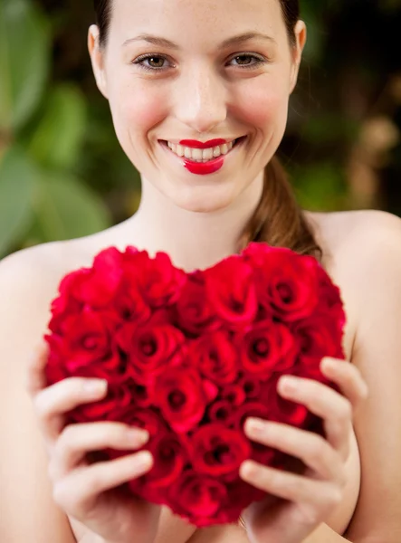 Nacktes Mädchen mit einem roten Rosenherz in einem Garten — Stockfoto