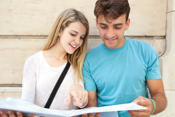 Tourist couple looking and pointing at a map in city — Stock fotografie