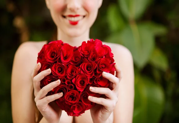 Nude girl holding a red roses heart in a garden — Stok fotoğraf