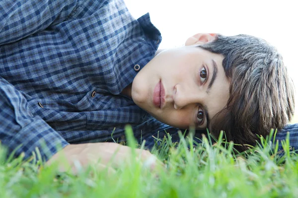 Rapaz que estabelece na grama verde em um parque — Fotografia de Stock