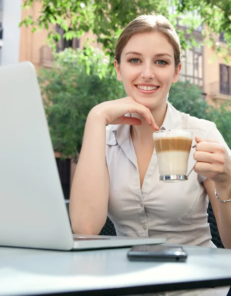 Mujer de negocios beber una bebida y el uso de la computadora portátil — Foto de Stock