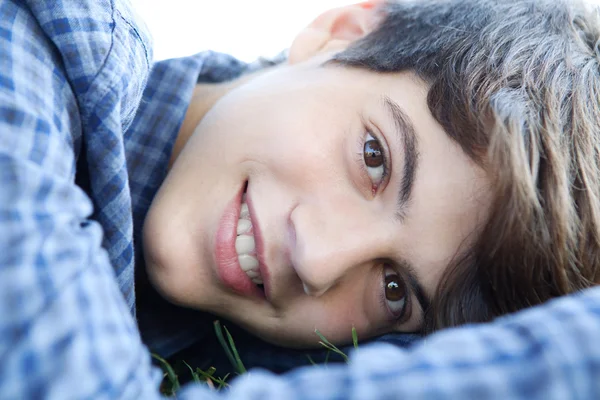 Boy laying down on green grass in a park — Φωτογραφία Αρχείου