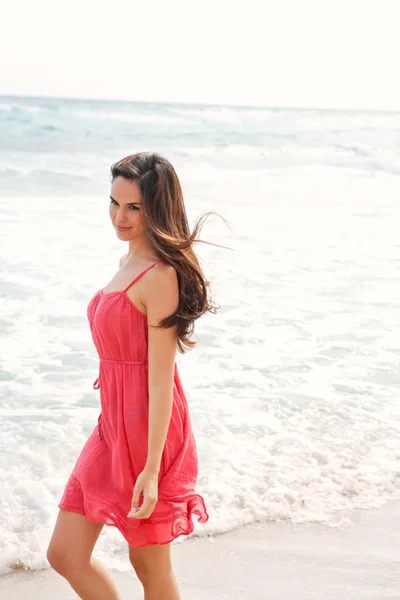 Mulher andando em uma praia com as ondas do mar salpicando — Fotografia de Stock