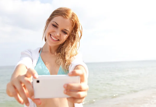 Woman taking selfies pictures on the beach — Stockfoto