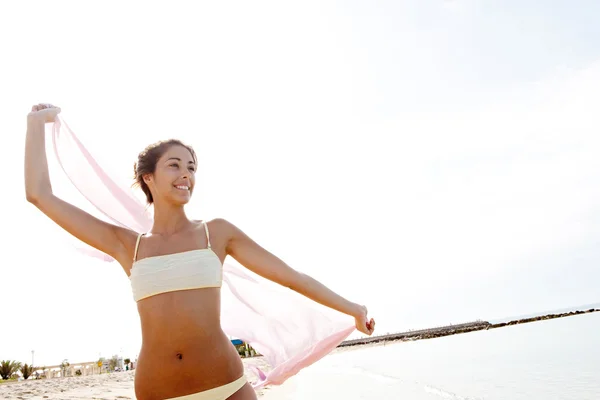 Jeune femme avec un sarong en tissu rose sur la plage — Photo