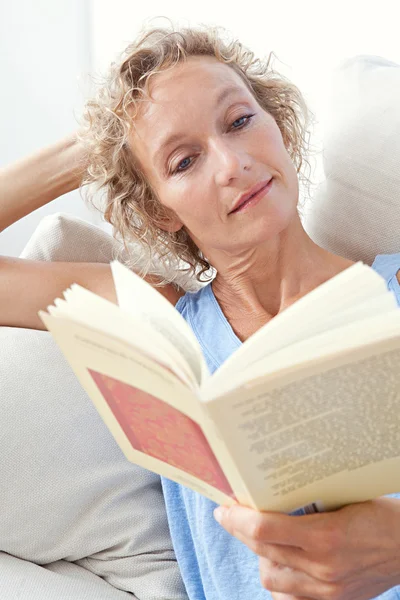 Frau liest Buch zu Hause auf dem Sofa — Stockfoto