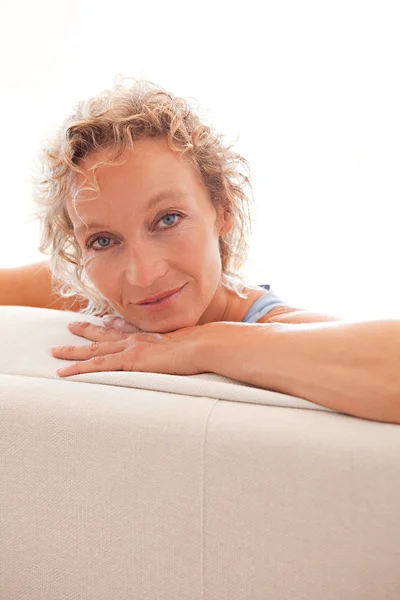 Mulher relaxante em um sofá branco em casa — Fotografia de Stock