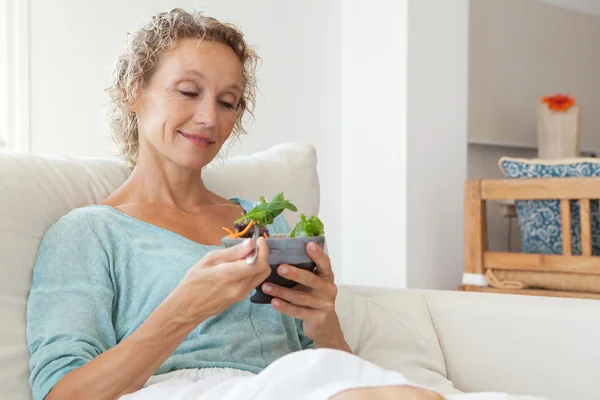 Frau isst Salat auf der Couch zu Hause — Stockfoto