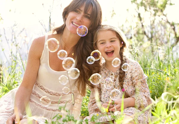 Mother and daughter playing to blow floating bubbles — ストック写真