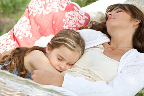 Daughter and her mother laying together in a hammock — Stockfoto