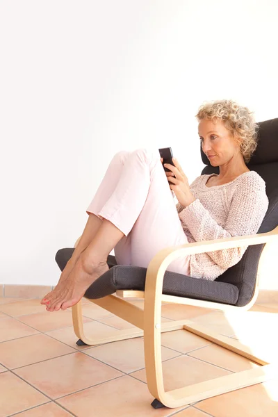 Woman in an armchair using a smartphone — Stock Photo, Image
