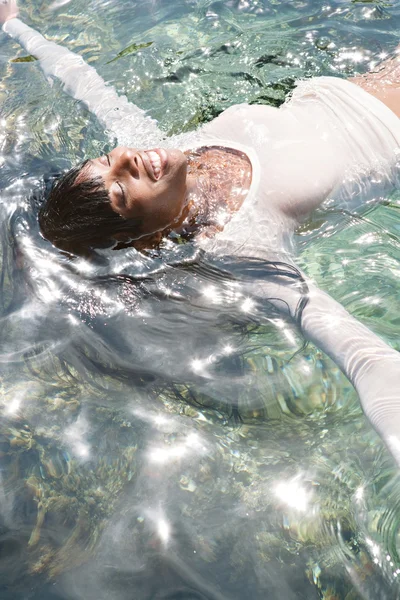 Black woman swimming and floating in a sea — Stockfoto