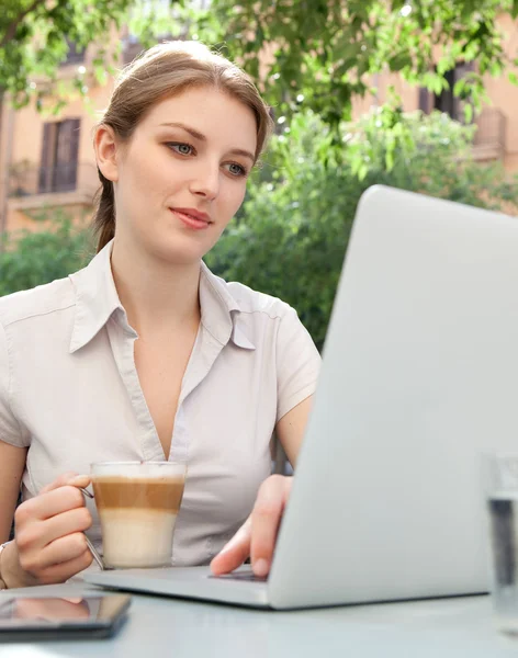 Mulher de negócios bebendo uma bebida e usando laptop — Fotografia de Stock