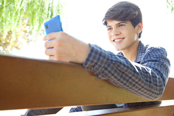 boy using his smartphone device on a wooden bench