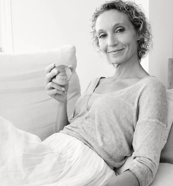 Donna che mangia una mela su un divano a casa — Foto Stock