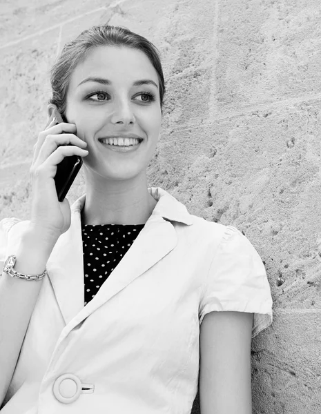 Business woman using a smartphone near a wall — Zdjęcie stockowe