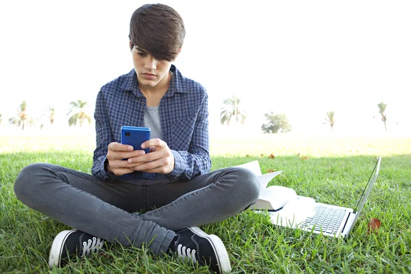 Junge benutzte sein Smartphone auf dem Rasen — Stockfoto