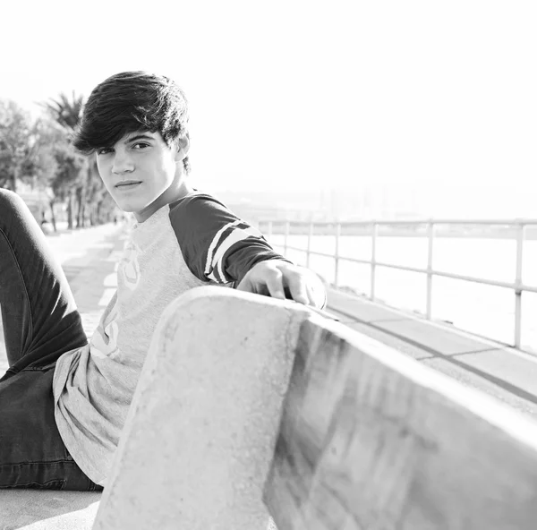 Boy relaxing and sitting on a bench by the sea — Stok fotoğraf