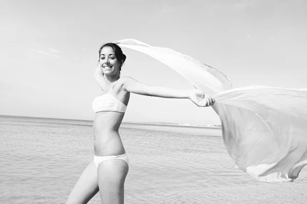 Donna su una spiaggia che regge un tessuto rosa — Foto Stock