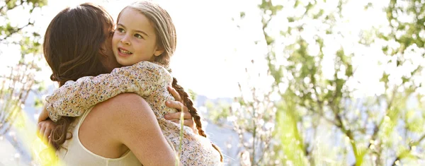 Mãe e filha abraçando em um campo de primavera — Fotografia de Stock