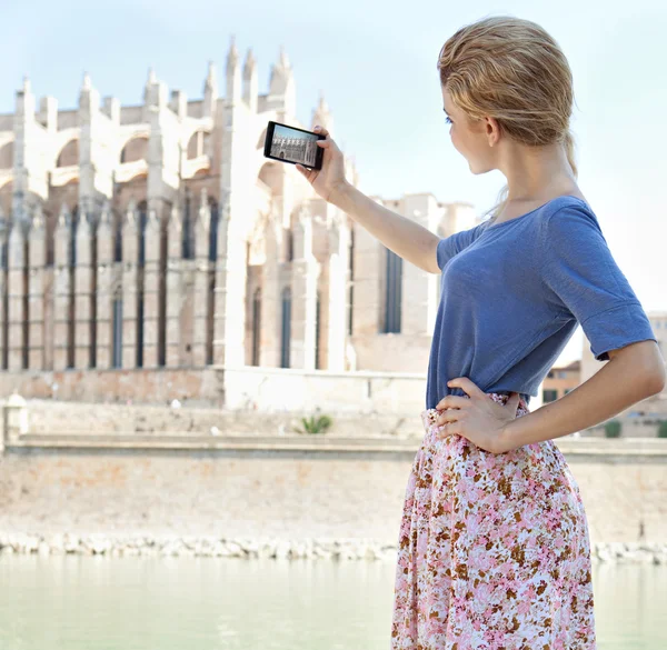 Girl using a smartphone to take photos of a cathedral — 图库照片