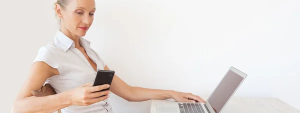 Mulher usando um dispositivo smartphone e um computador portátil — Fotografia de Stock