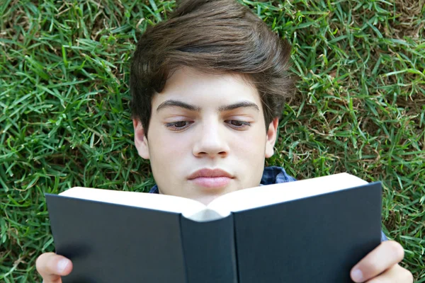 Menino lendo um livro sobre a grama — Stockfoto