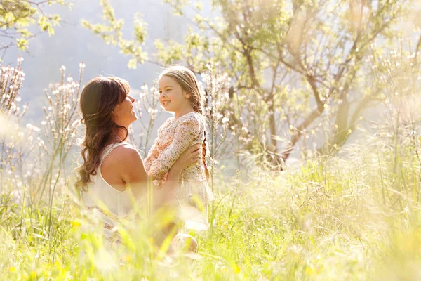 Mother and daughter hugging in a spring field — Stok fotoğraf