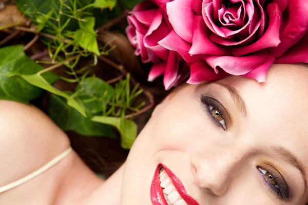 Woman laying in a forest wearing a red roses head dress — Stock Photo, Image