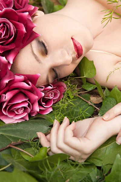 Woman laying in a forest wearing a red roses head dress — Stok fotoğraf