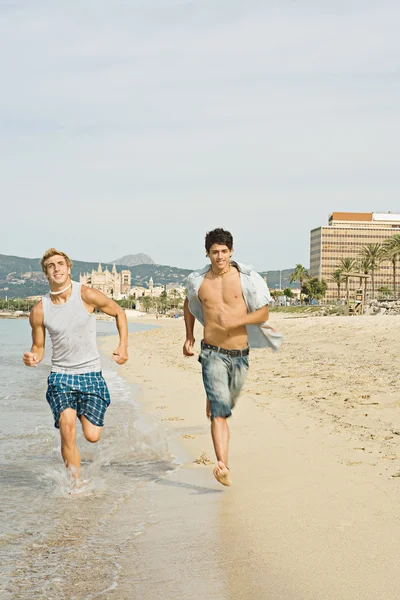 Друзья, бегущие вместе по пляжу — стоковое фото