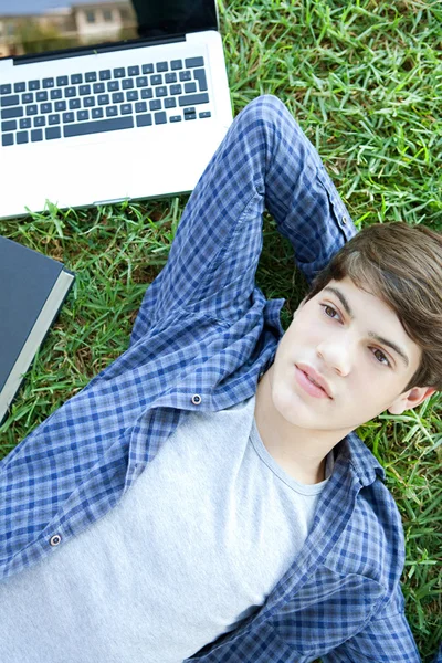 Boy laying down on green grass in a park — Stok fotoğraf