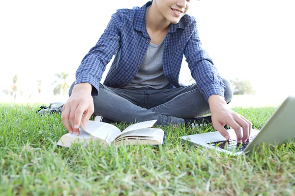 Boy with an open book using a laptop — Stock fotografie