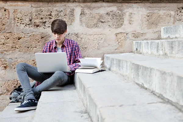 Menino com livros escolares e um computador portátil — Fotografia de Stock