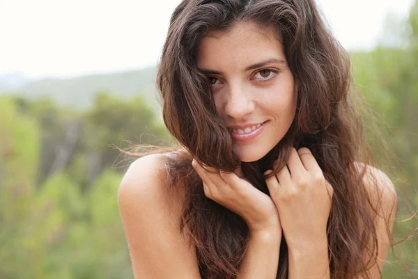 Mujer sosteniendo su cabello y sonriendo en la naturaleza — Foto de Stock